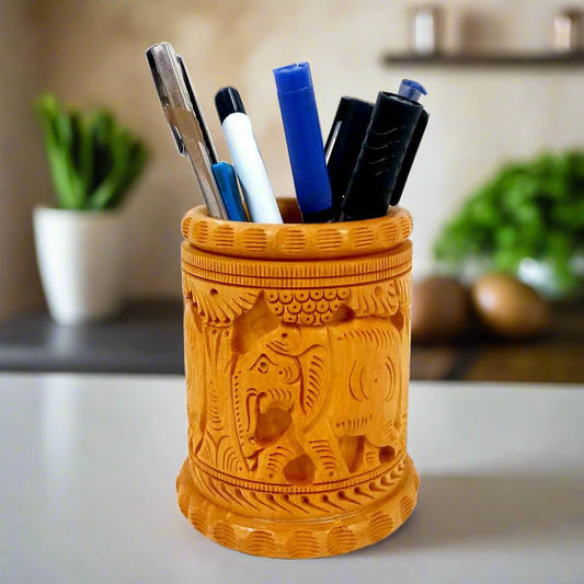 A handcrafted, round-shaped wooden pen holder with carvings of two elephants and tree plants.