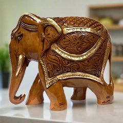 A beautiful wooden carved elephant with a downward-facing trunk and intricate carvings.