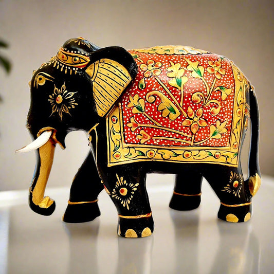 Wooden elephant with low trunk, black body, and luxurious gold floral emboss painting on back and stomach, ideal for home decor and gifting