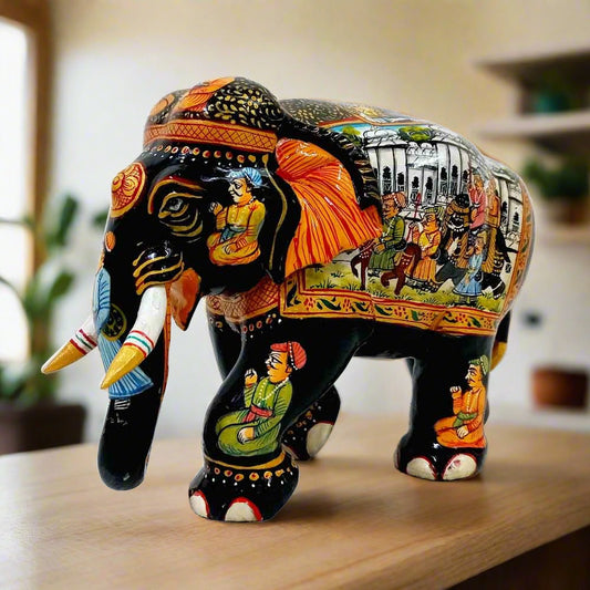 Wooden elephant statue adorned with intricate Mughal miniature paintings on trunk, face, legs, and back, featuring multicolored designs and black body.