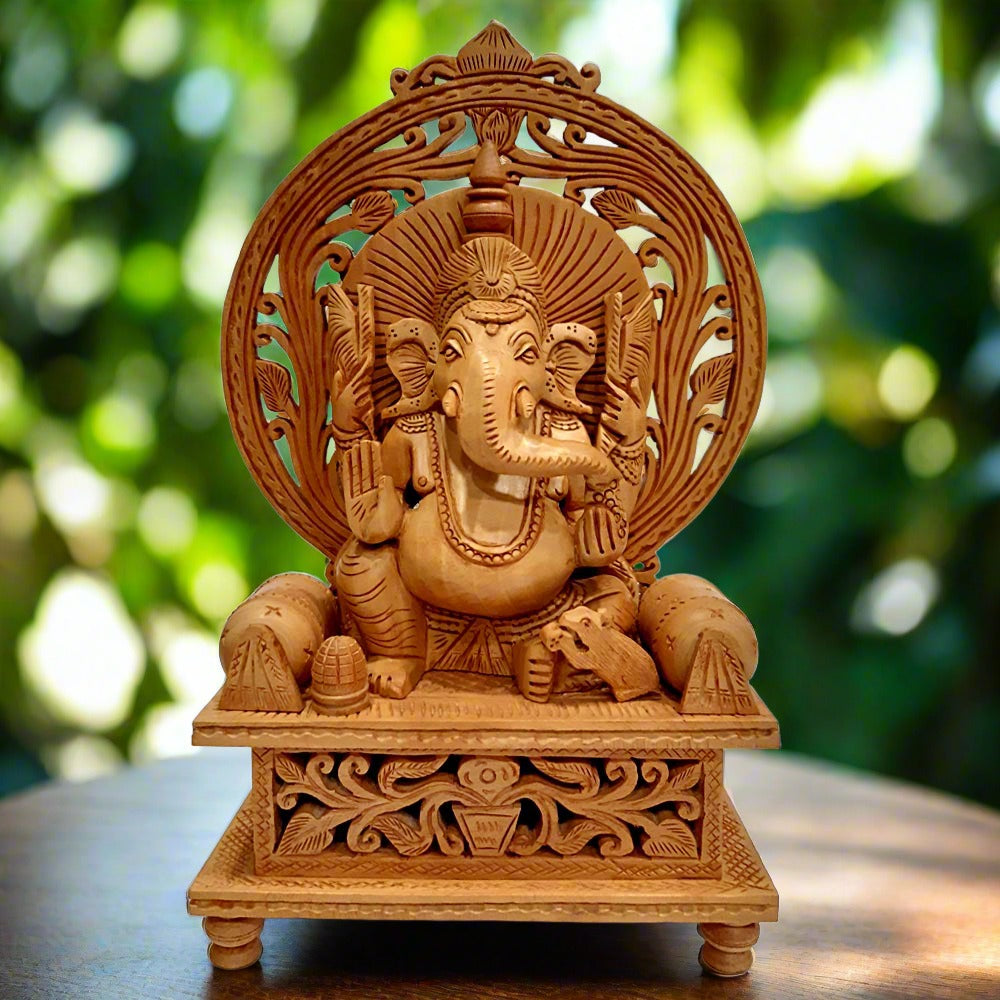 Intricately hand-carved wooden Ganesh idol sitting with a rat on a singhasan decorated with undercut leaf and bolster pillow designs.