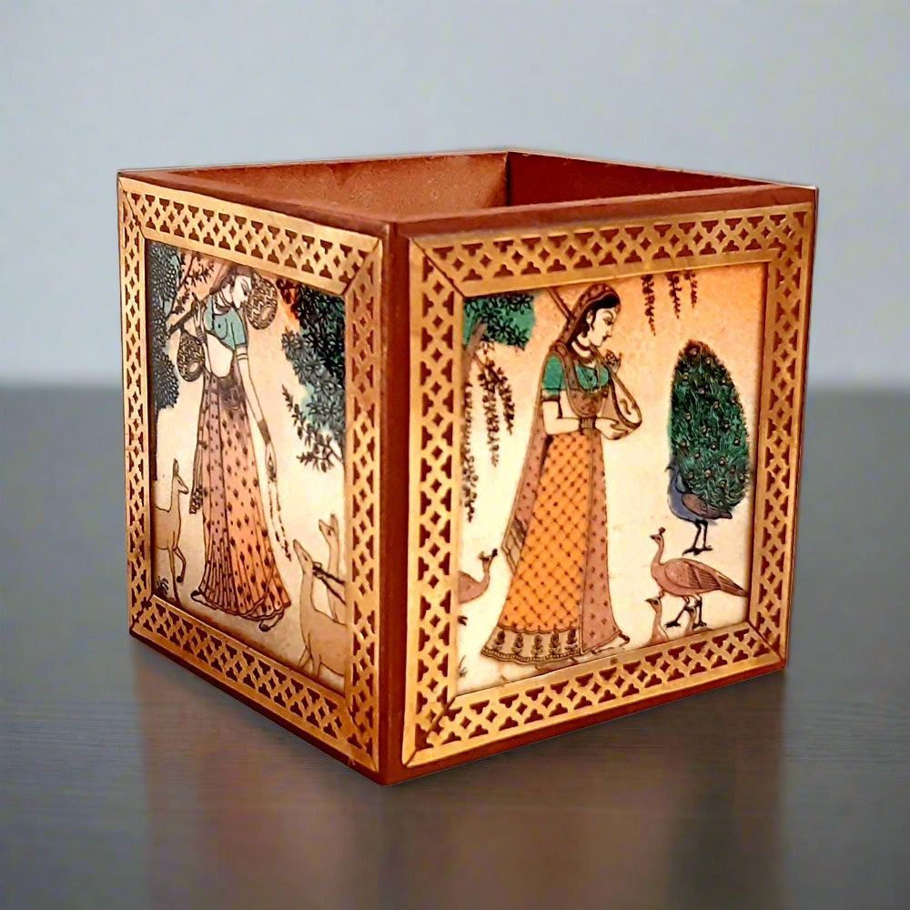 A handmade wooden pen stand decorated with a gemstone painting of a lady and a pure brass border.