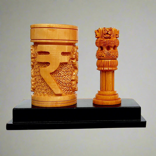 A wooden pen stand with a carved Indian Rupee symbol and a National Emblem Ashok Pillar on a black base.