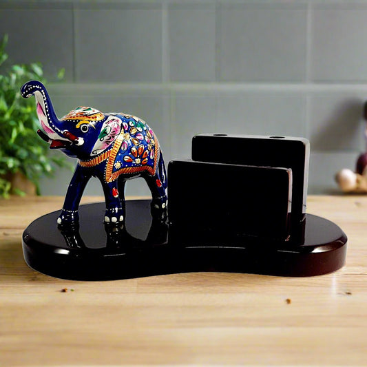 A wooden pen stand with a metal lucky elephant, beautifully decorated with Meenakari painting.