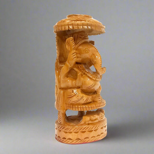 Intricately detailed wooden Lord Ganesh figurine seated under an umbrella, perfect for pooja decor