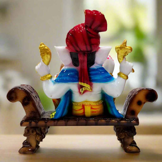 Innovative Lord Ganesha statue in a relaxed pose on a sofa, blending modern design with spiritual symbolism.