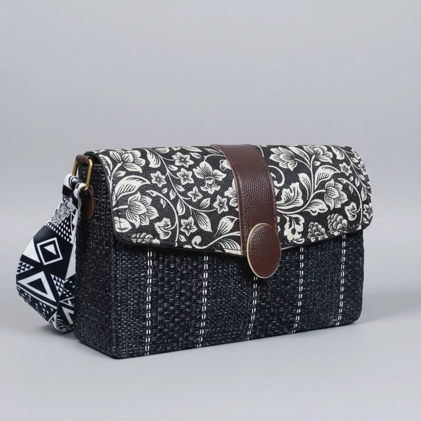 Profile of the compact handbag highlighting the matching black and white floral adjustable fabric sling.