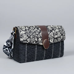 Profile of the compact handbag highlighting the matching black and white floral adjustable fabric sling.