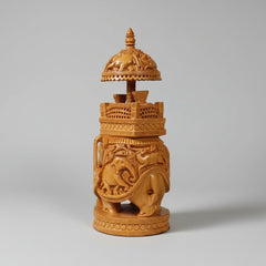 Side profile of a wooden elephant statue with high-depth reliefs of smaller elephants and forest deer.