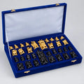 Natural wood-toned and black Ambabari chess pieces arranged in a blue-lined storage box with a velvet box