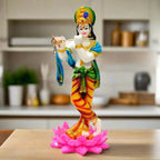 A beautiful marble dust standing Krishna idol playing the flute, on a lotus flower.