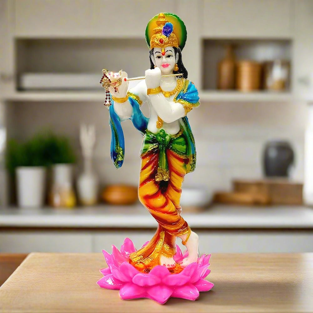 A beautiful marble dust standing Krishna idol playing the flute, on a lotus flower.