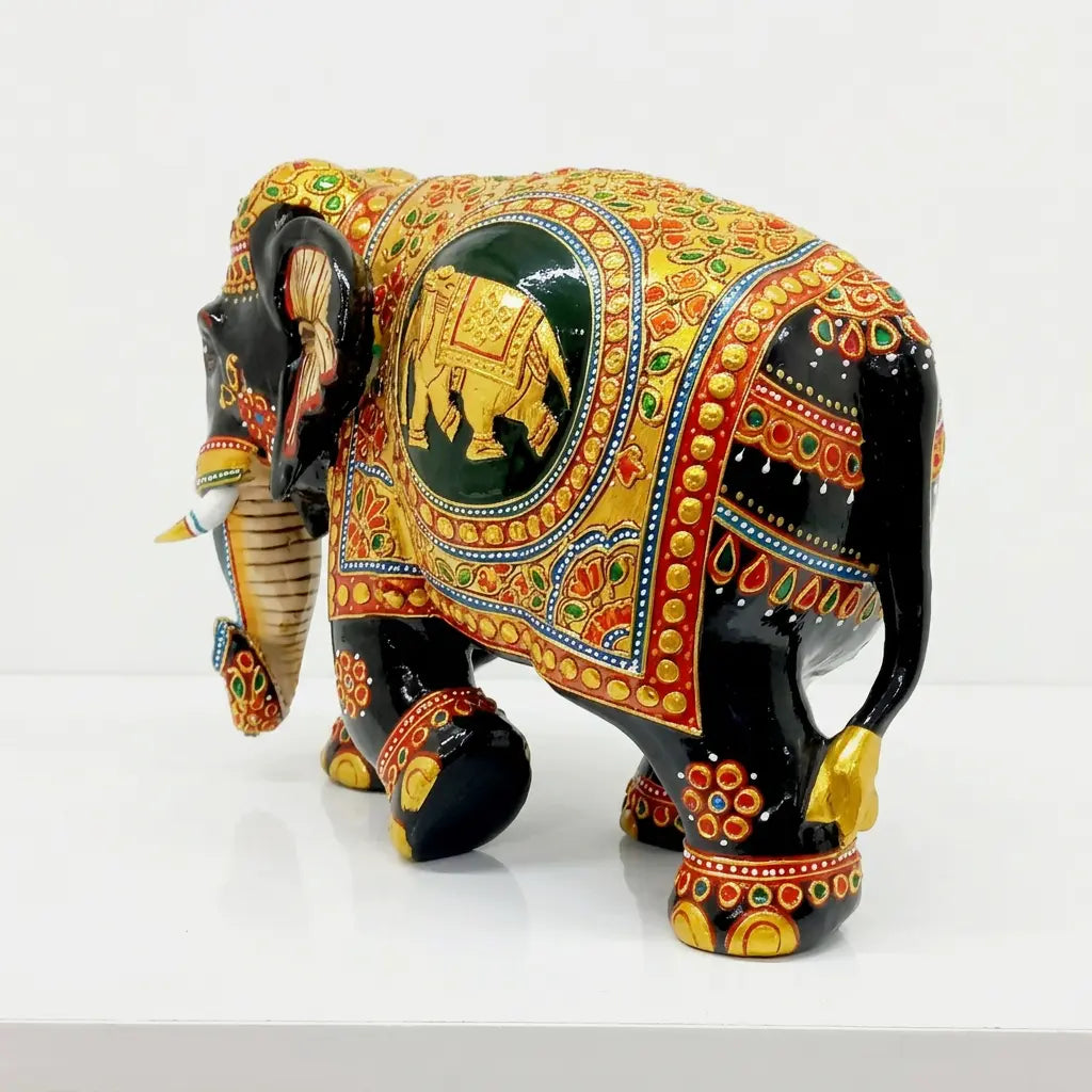 Rear angled view of black and gold wooden elephant showing the ornamental side panel, decorated legs and gold-tipped tail