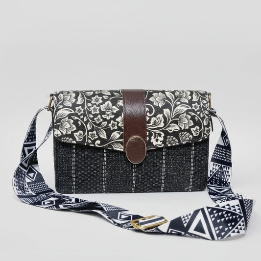 Women’s black and white floral sling bag with a textured woven fabric body and premium black PU leather accents.