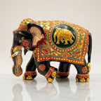 Left-facing black wooden elephant with a golden elephant motif inside a green circular panel and colourful floral borders