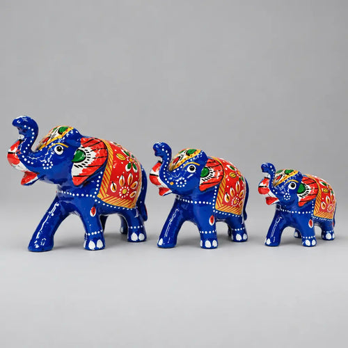 Front angled view of three blue Meenakari elephants with raised trunks and red, green and gold detailing