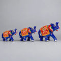 Three blue Meenakari elephant figurines in ascending sizes with red floral saddle designs, facing right