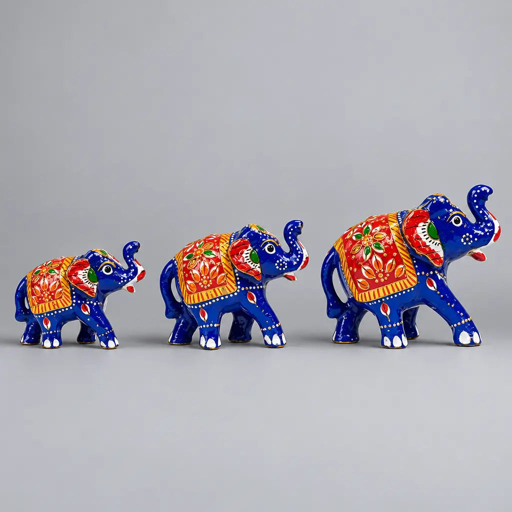 Three blue Meenakari elephant figurines in ascending sizes with red floral saddle designs, facing right
