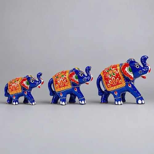 Three blue Meenakari elephant figurines in ascending sizes with red floral saddle designs, facing right