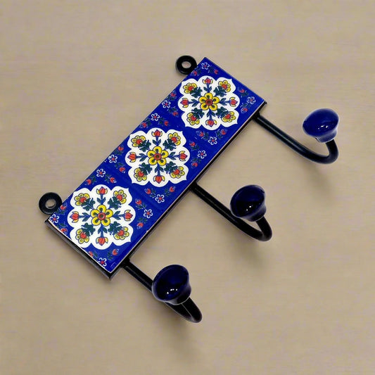 A decorative Blue Pottery cloth hanger with 3 hooks for wall mounting.