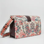 The side profile of the woven handbag highlighting the adjustable sling made from matching floral fabric.