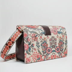 The side profile of the woven handbag highlighting the adjustable sling made from matching floral fabric.
