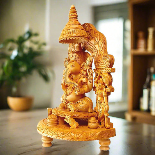 A beautifully carved wood Ganesh idol giving blessings and holding laddoos, with Riddhi and Siddhi on either side.