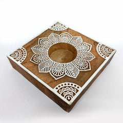 A carved wooden candle holder, a stylish addition to a living room or bedroom.