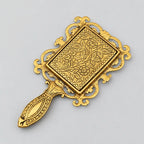 Back view of a decorative metal hand mirror with a golden finish, engraved flowers and leaves, and an ornate handle.