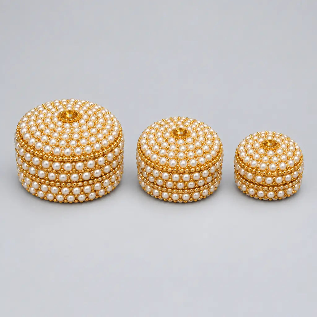 Three closed round lac kumkum boxes in graduated sizes, decorated with pearl-style bead rows, golden accents and central lid stones.