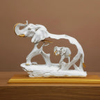 White and gold elephant statue with mother trunk up and baby calf on golden base
