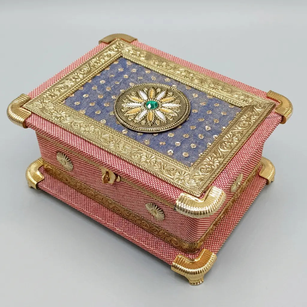 Closed pink dry fruit gift box with a purple lid panel, circular floral ornament and gold-tone borders