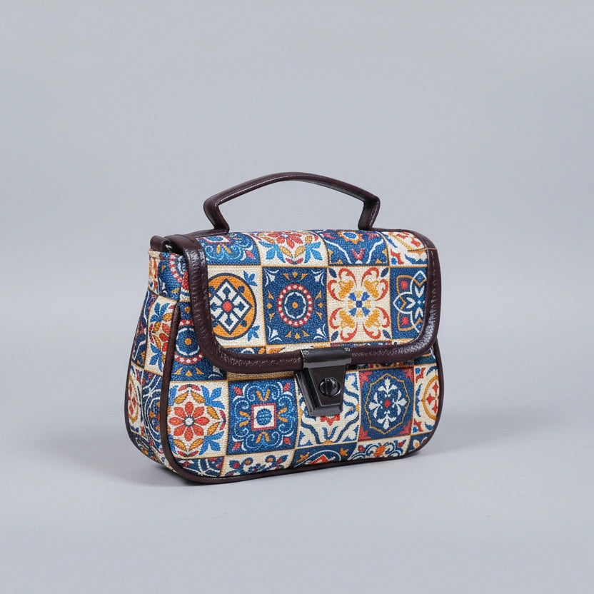 Front view of a small floral ethnic sling bag with button closure and handle