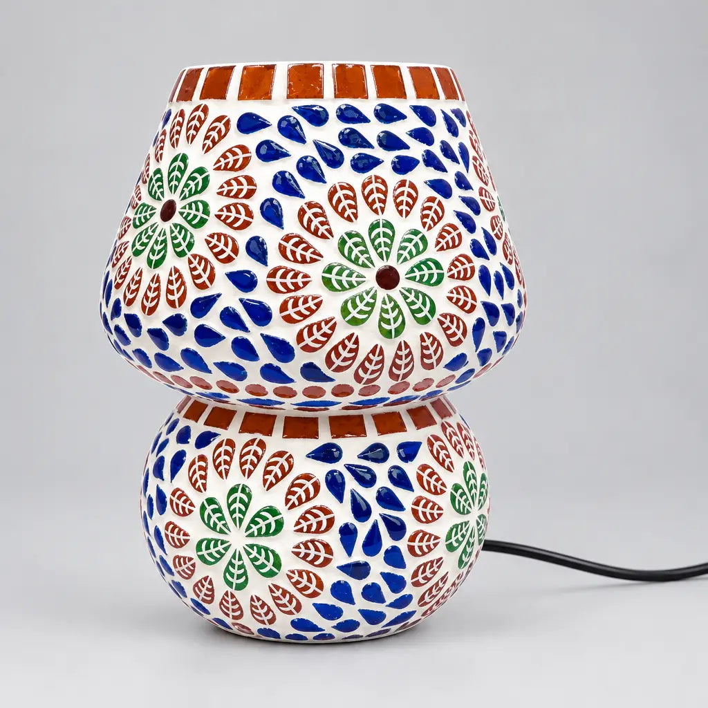 Floral mosaic glass table lamp with blue, green and reddish-brown tiles on its shade and rounded base, shown unlit.