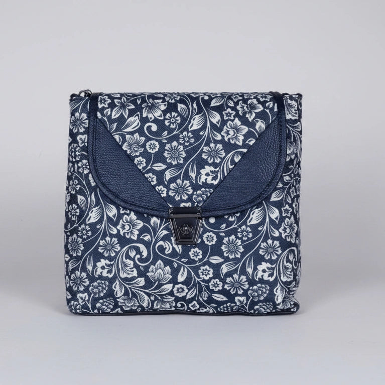 Front view of a 10x10 inch black sling bag with floral motifs and a front flap button closure