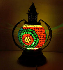 A decorative table lamp with a mosaic pattern, made from glass, wood, and metal.