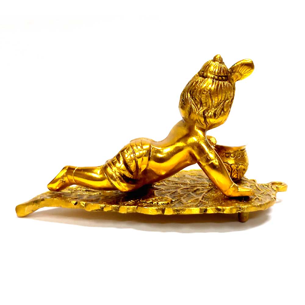 Krishna idol on leaf made of metal with intricate carvings and golden polish.