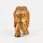 Front view of golden wooden elephant with embossed floral motifs on its forehead and colourful detailing along the trunk