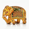 Left-facing golden wooden elephant with a deep green panel, colourful embossed floral patterns and white tusks