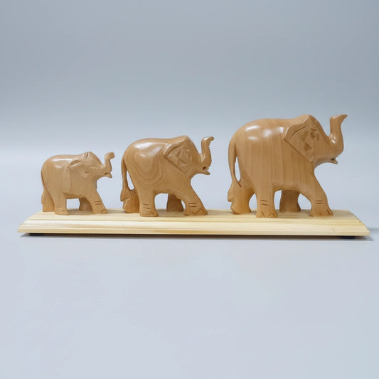 A 9-inch long hand-carved elephant family trio made from premium Kadamb wood, featuring a natural matte finish and intricate artisanal details on a solid wooden base.