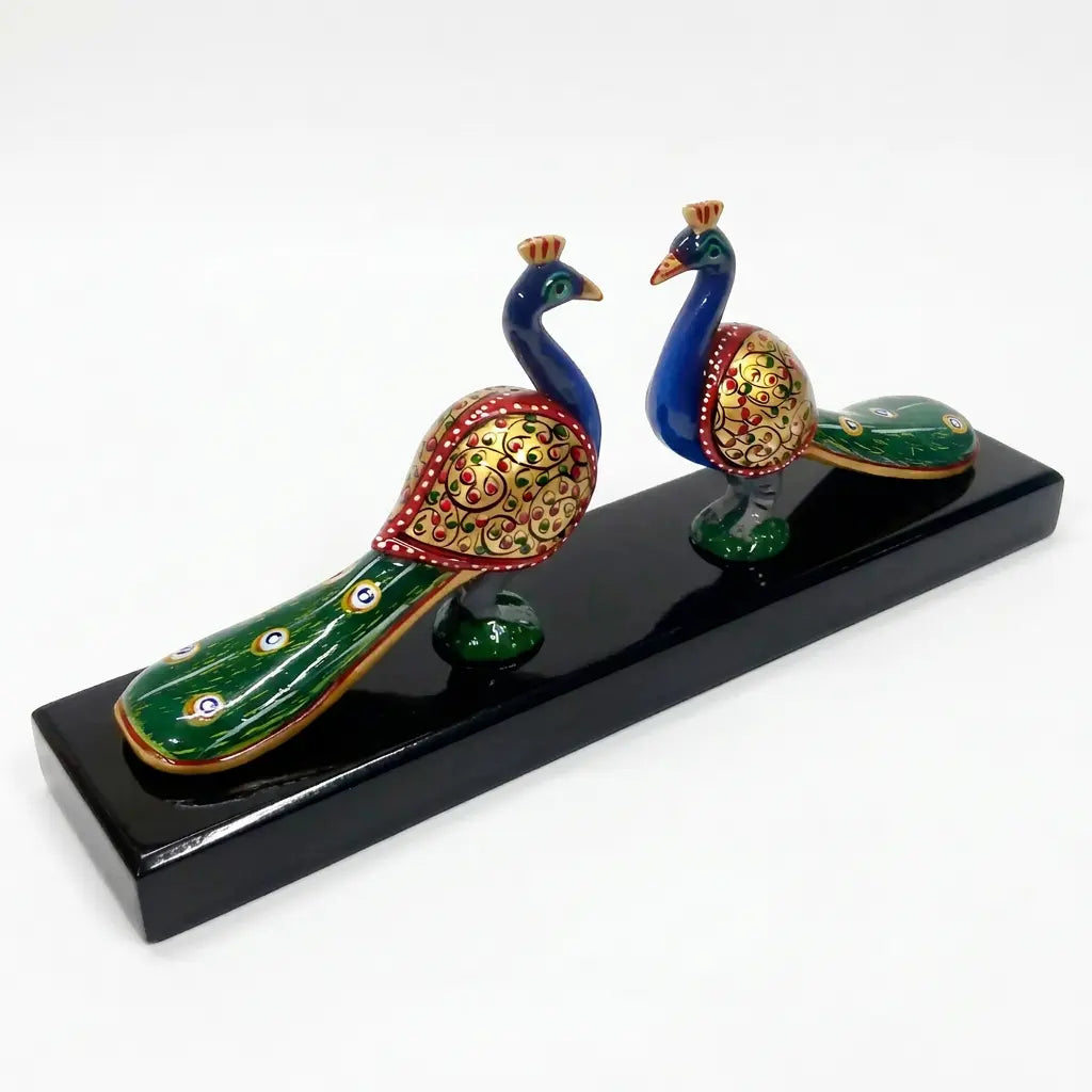 Hand-painted pair of wooden peacocks displayed on a wooden platform