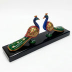 Hand-painted pair of wooden peacocks displayed on a wooden platform