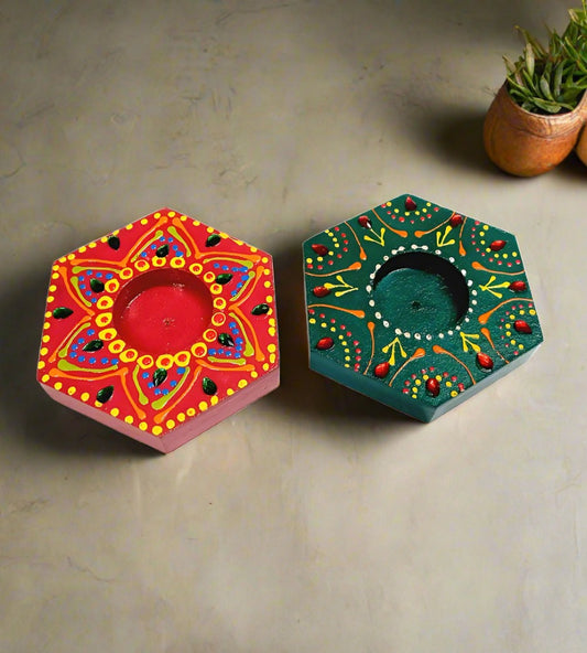 A set of two hand-painted wooden candle holders with a decorative finish.