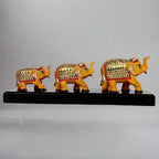 Set of three hand-painted wooden elephants of varying sizes standing on a decorative wooden bridge.
