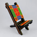 Hand painted wooden phone holder in a folding chair shape with red, green, orange and blue floral patterns.