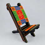 Hand painted wooden phone holder in a folding chair shape with red, green, orange and blue floral patterns.