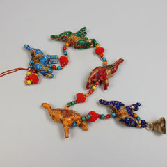 Close-up of handmade embroidered elephant hanging with decorative pompoms and a brass bell.