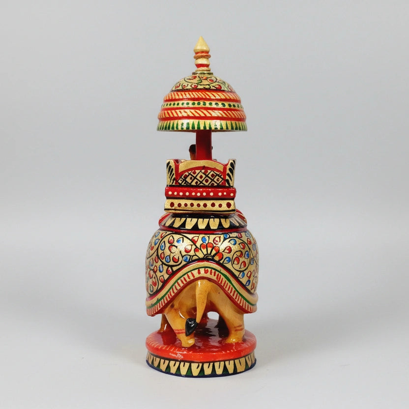 Rear profile of a wooden elephant showing continuous hand-painted designs and gold-colored accents.