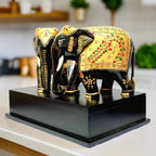 An angled view of the handmade elephant statues on their black platform, highlighting the vibrant green and black color accents.