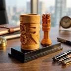 Close-up of a wooden pen holder with carved Rupee symbol and floral details beside an Ashoka Pillar on a black base